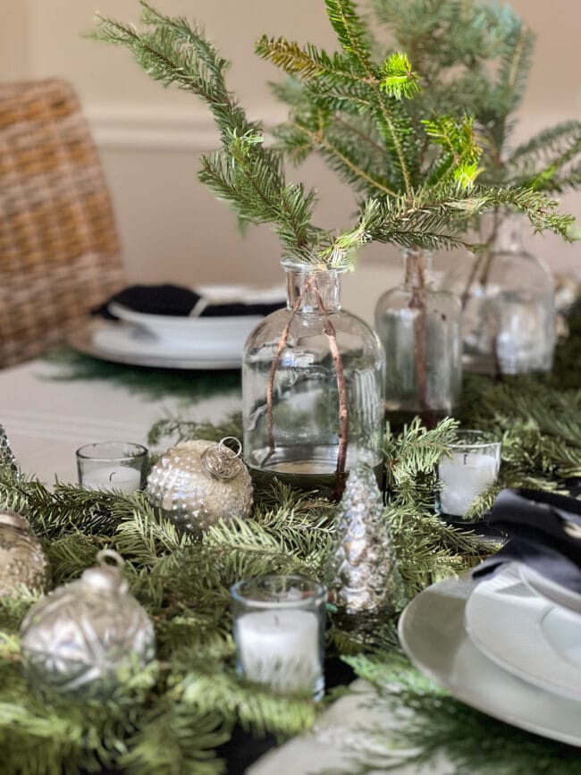 fresh greens with bottles and silver ornaments as holiday table centerpiece