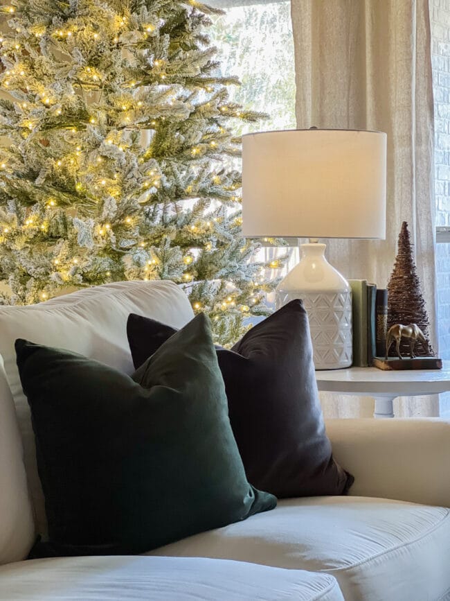green and gray velvet pillows on white sofa with flocked tree in background