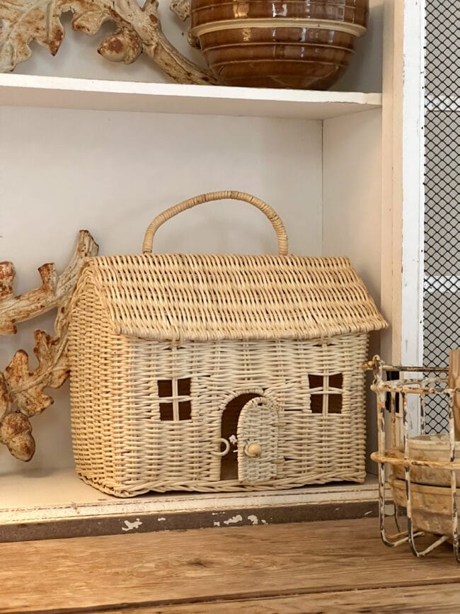 small wicker house basket sitting on shelf