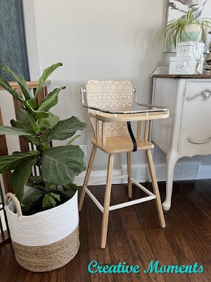 vintage highchair with fig tree and white buffet in background