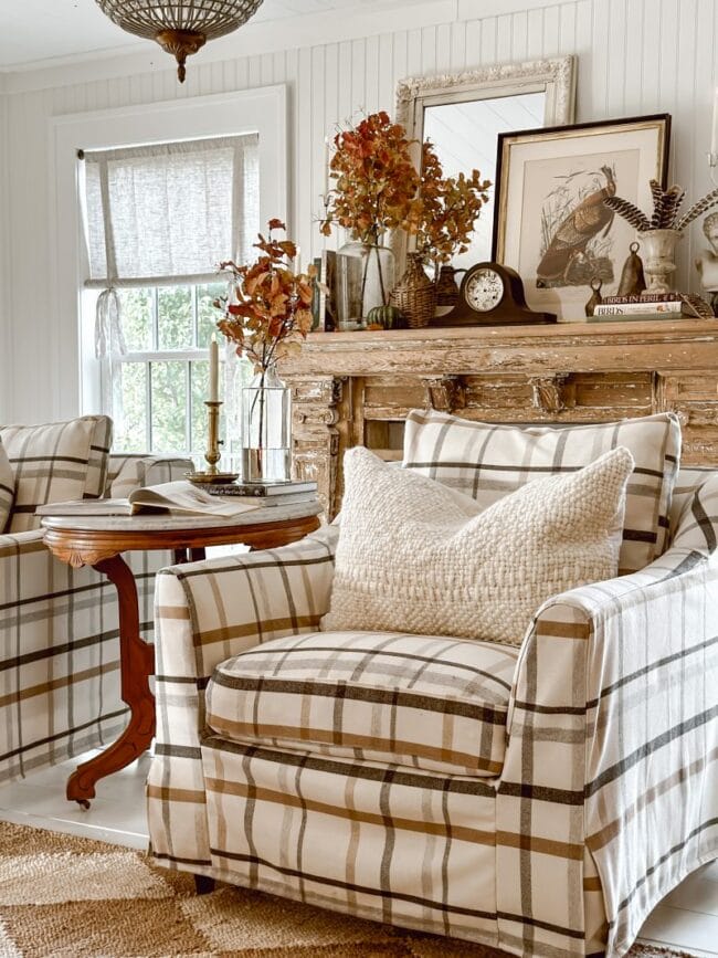 brown plaid chair with cream nubby pillow and wood mantel behind it