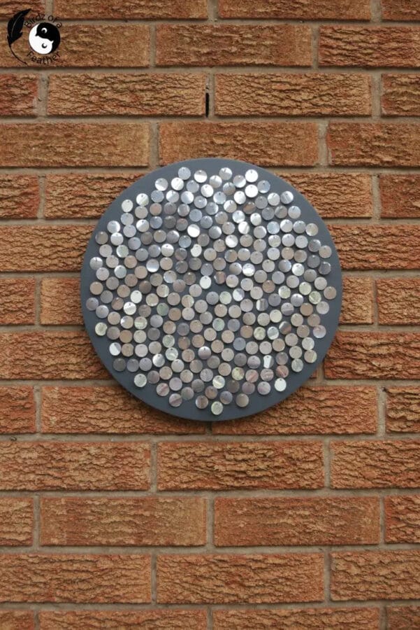 circular wall art made of small circles hanging on brick wall