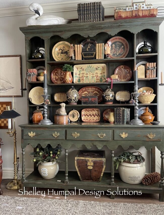 Olive green dining hutch with several plates and vases