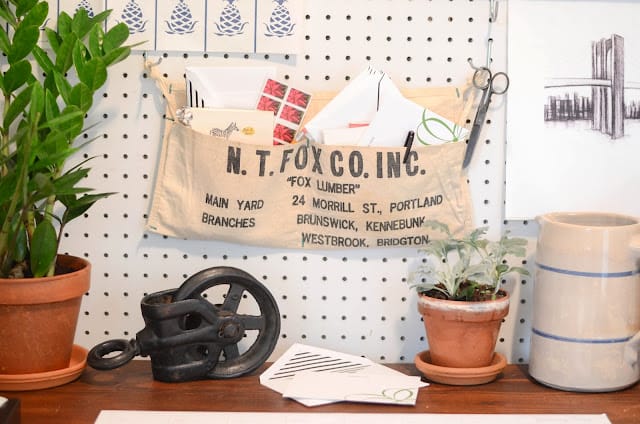 antique hardware apron hanging on peg wall with plants and a crock pitcher