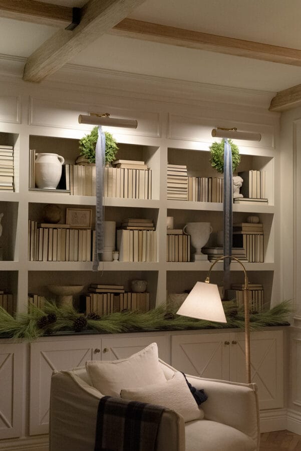 cream colored chair with floor lamp and bookshelves with sconces behind it