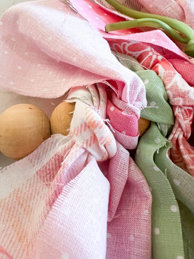 close up of pink and green scraps of fabric tied around wood bead wreath