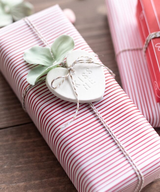 red and white striped gift box with a white Kiss Me heart on top
