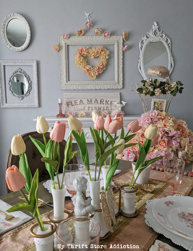 table setting with pink tulips in white cases with vintage dishes