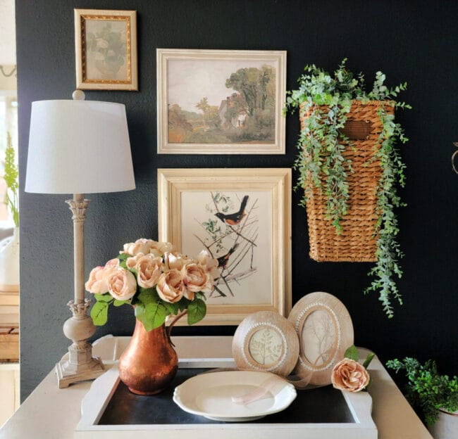 wall collage of prints, basket of greenery and lamp