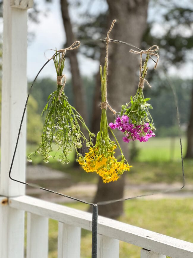 3 bunches of wildflowers hanging on a vintage birdcage holder