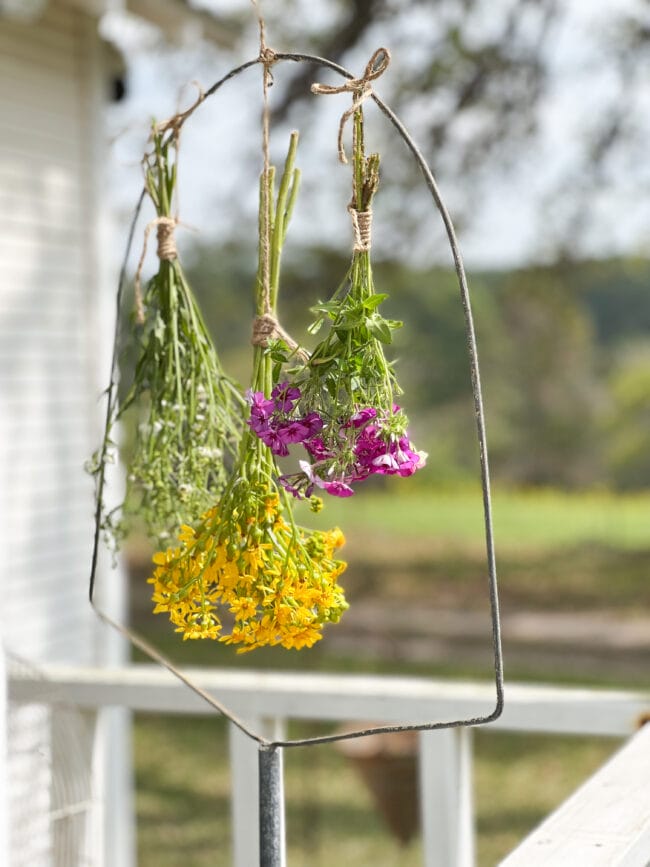 3 bunches of wildflowers hanging in vintage birdcage stand