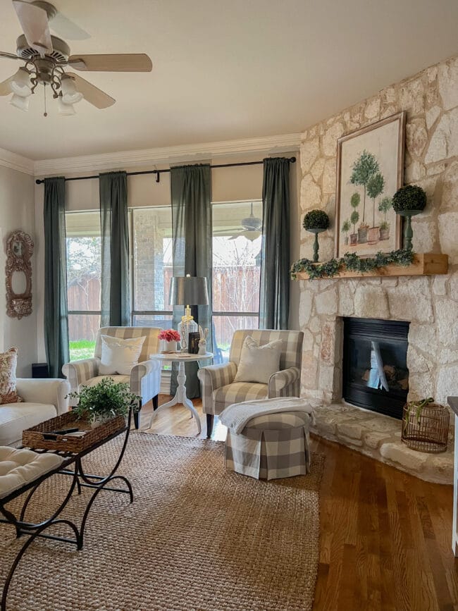 mantel with topiary print, windows with green curtains and plaid chairs