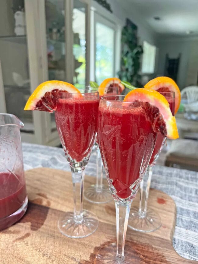 3 glasses of blood orange mimosas with slices on rim