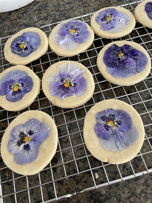 a tray of sugar cookies with purple pansies on top