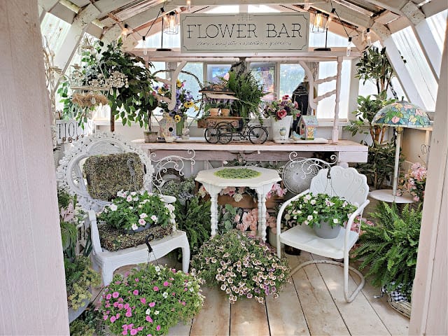 room with white metal chairs and lots of plants with flowers