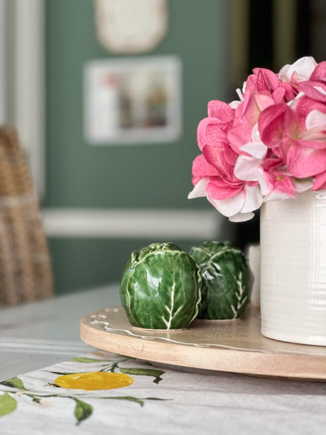 close upt of green cabbage salt and pepper shakers and pink faux flowers
