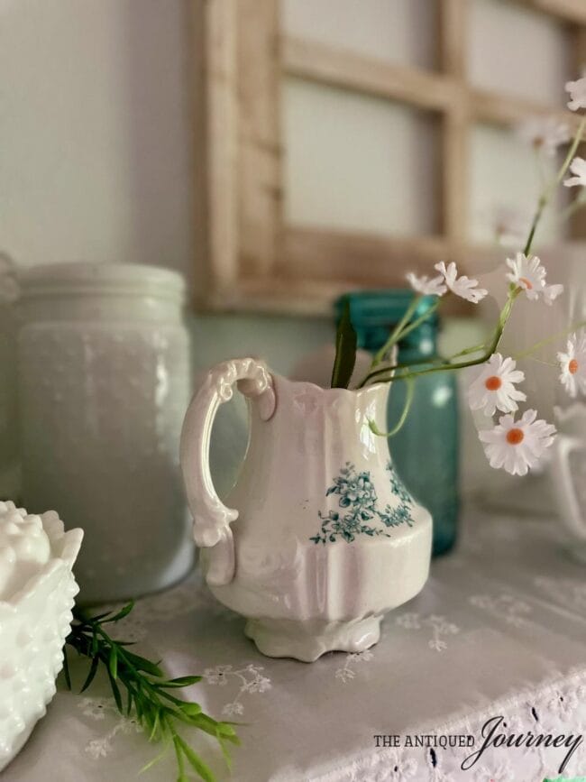 white antique ironstone pitcher with small daisies inside
