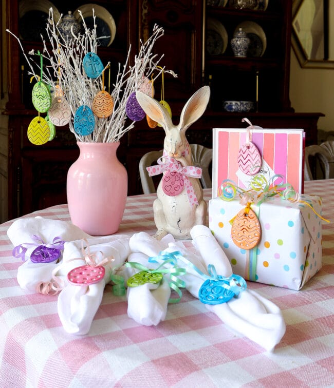 napkin rings, egg tree in a case, rabbit with a bow and gifts all with clay eggs hanging from them in bright colors