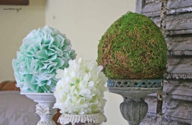 3 flowery egg shaped pieces sitting on gray candlesticks.