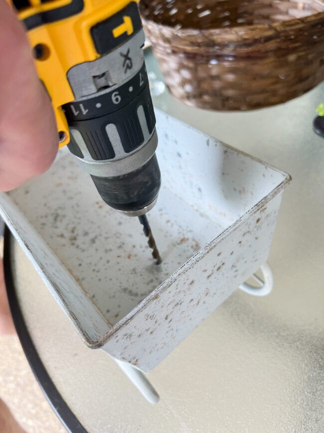 man drilling holes into a white metal container