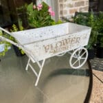 small white wheelbarrow sitting on a patio table