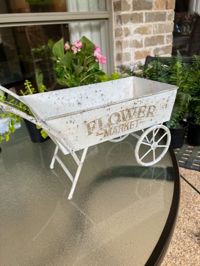 small white wheelbarrow sitting on a patio table