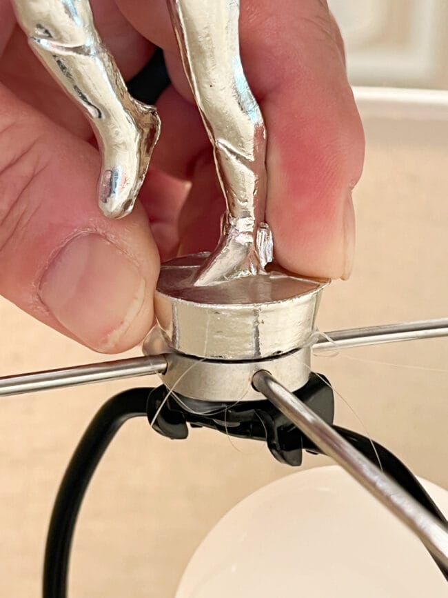 hand holding a trophy figure on top of a spider fitter and lampshade