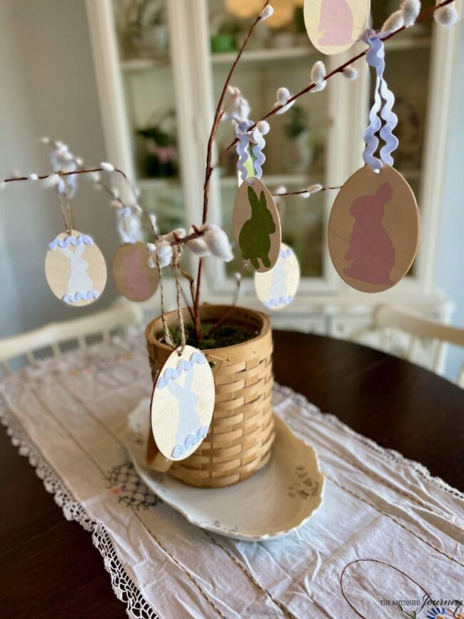 basket with a tree branch and wooden eggs hanging from the limb