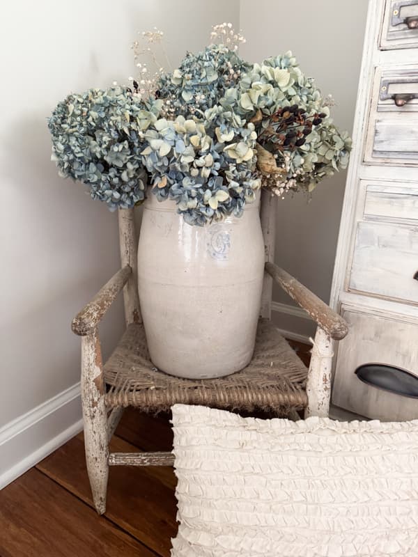 old crock with blue hydrangeas sitting in a old chippy childs chair