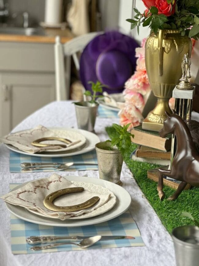 table setting with gold horseshoes, plastic horses and a purple hat
