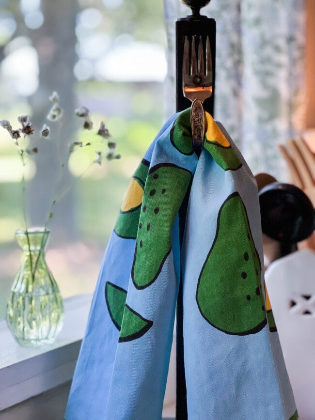 blue and green avocado dish towel hanging in front of a window 