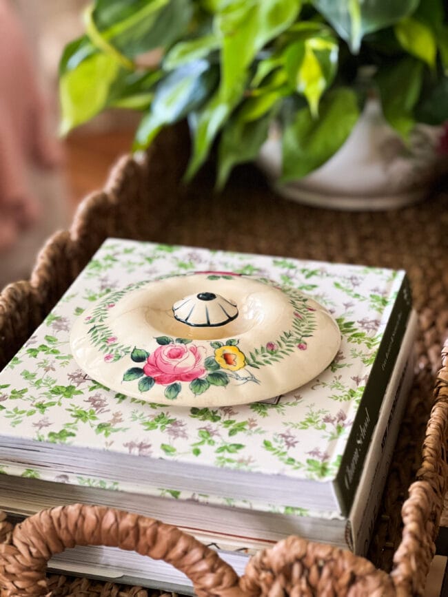 coffee table books with a vintage crock lid sitting on top