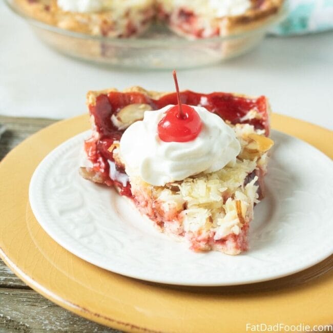 piece of cherry coconut pie on a white plate with a gold charger