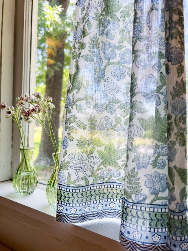 two green vases with fresh flowers and blue and green cafe curtains