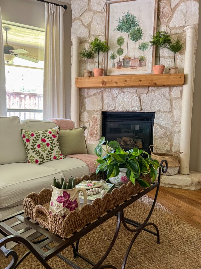 living room with stone fireplace, white sofa and a summer styled coffee table with vintage pots