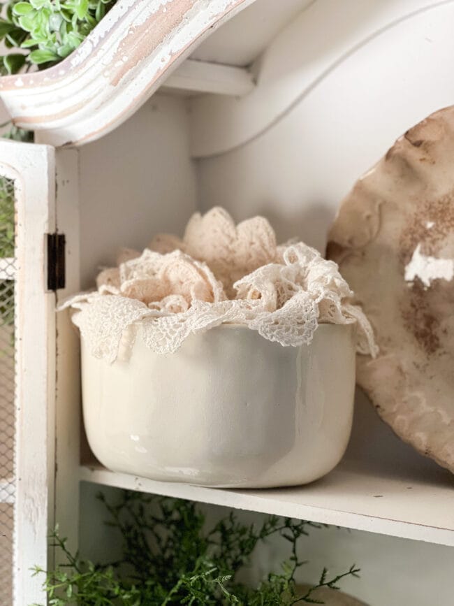 cream colored vintage mold with doilies stacked inside.