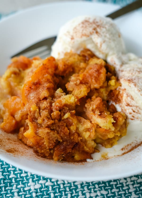 Peach Cobbler with vanilla ice cream on a white plate