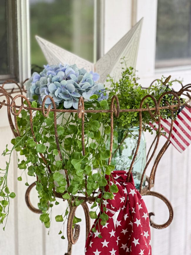 vintage metal basket with greenery, hydrangeas, a white star and a red scarf tied to the basket