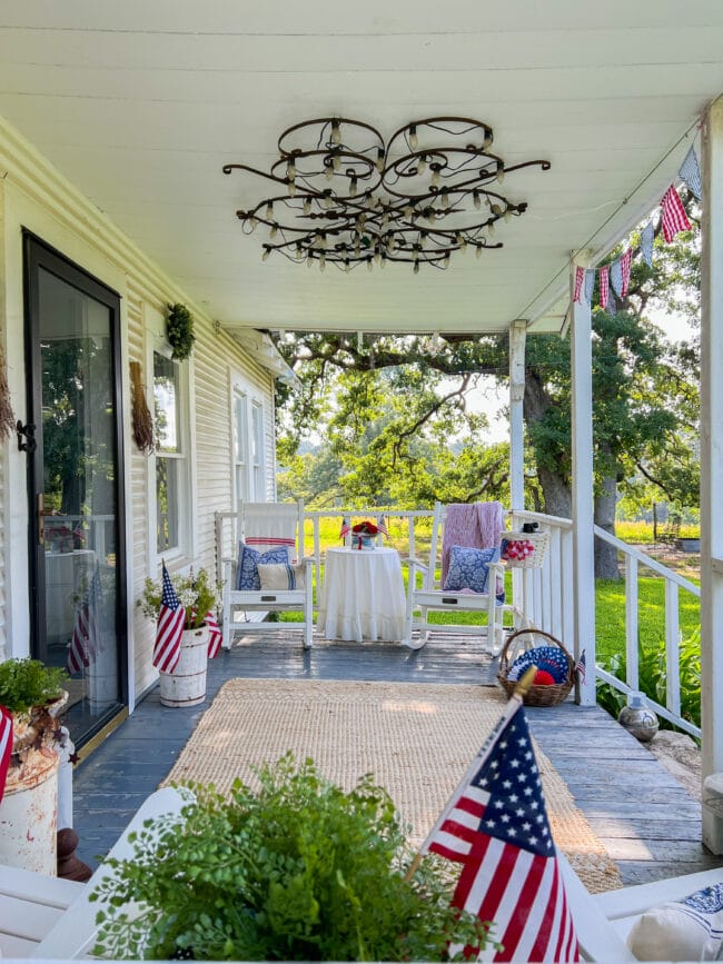 front porch with patriotic decor, rug, 2 chairs and skirted table