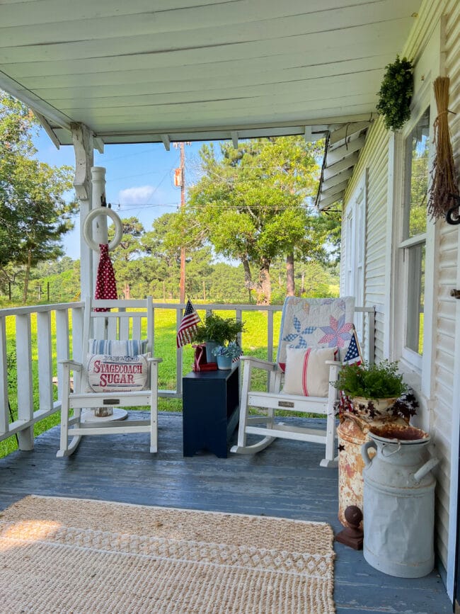 porch with 2 rocking chairs and patriotic decor and vintage milk cans
