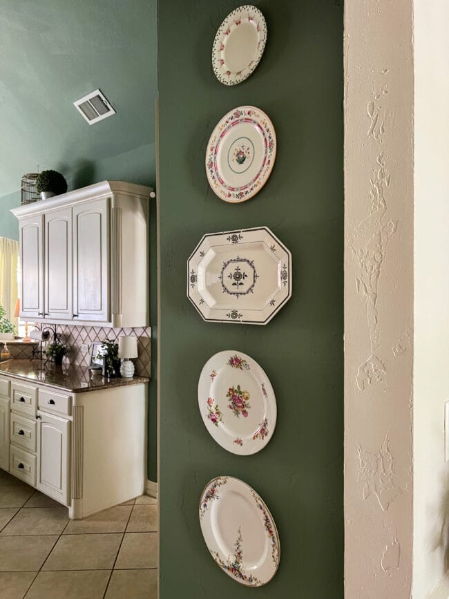 green kitchen walls with plates hanging and cream colored cabinets in the background