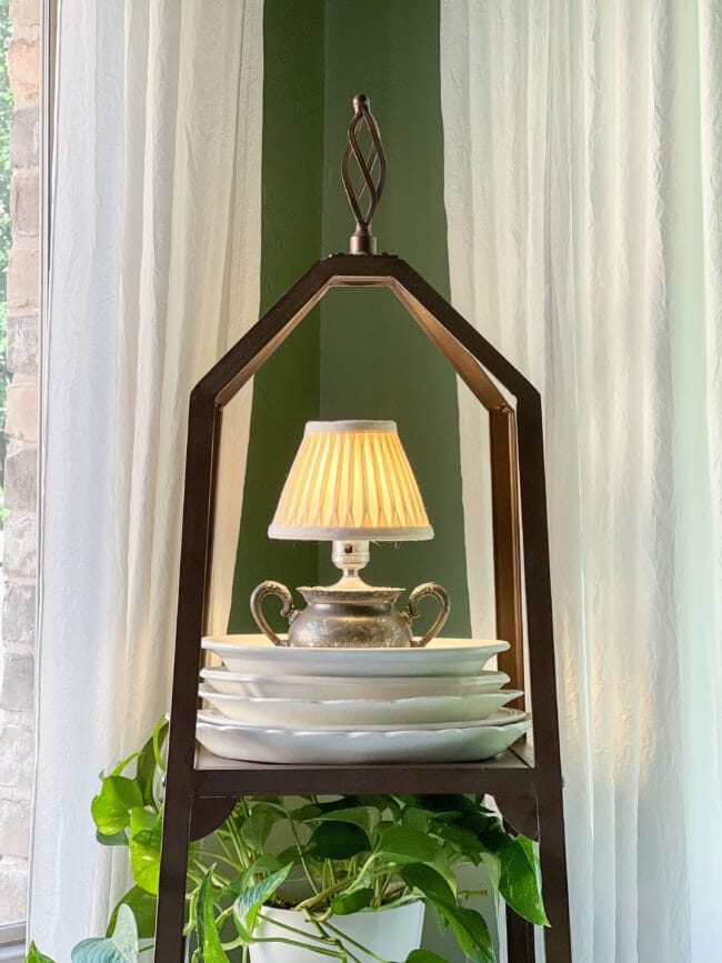 Etagere with white platters stacked and a small silver creamer lamp on top