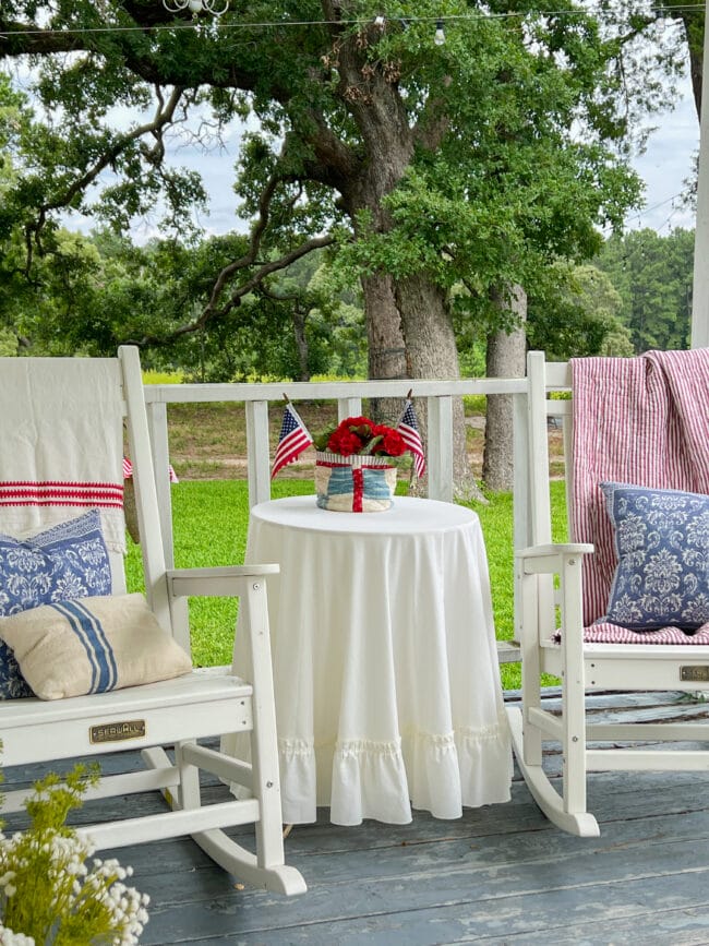 two rocking chairs with red and white quilts, pillows and a white skirted table