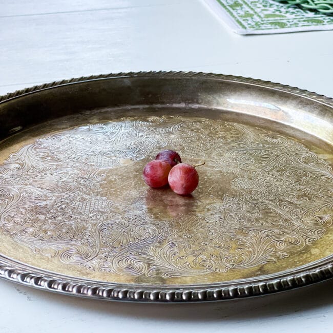 silver tray with 3 tiny red grapes in the center