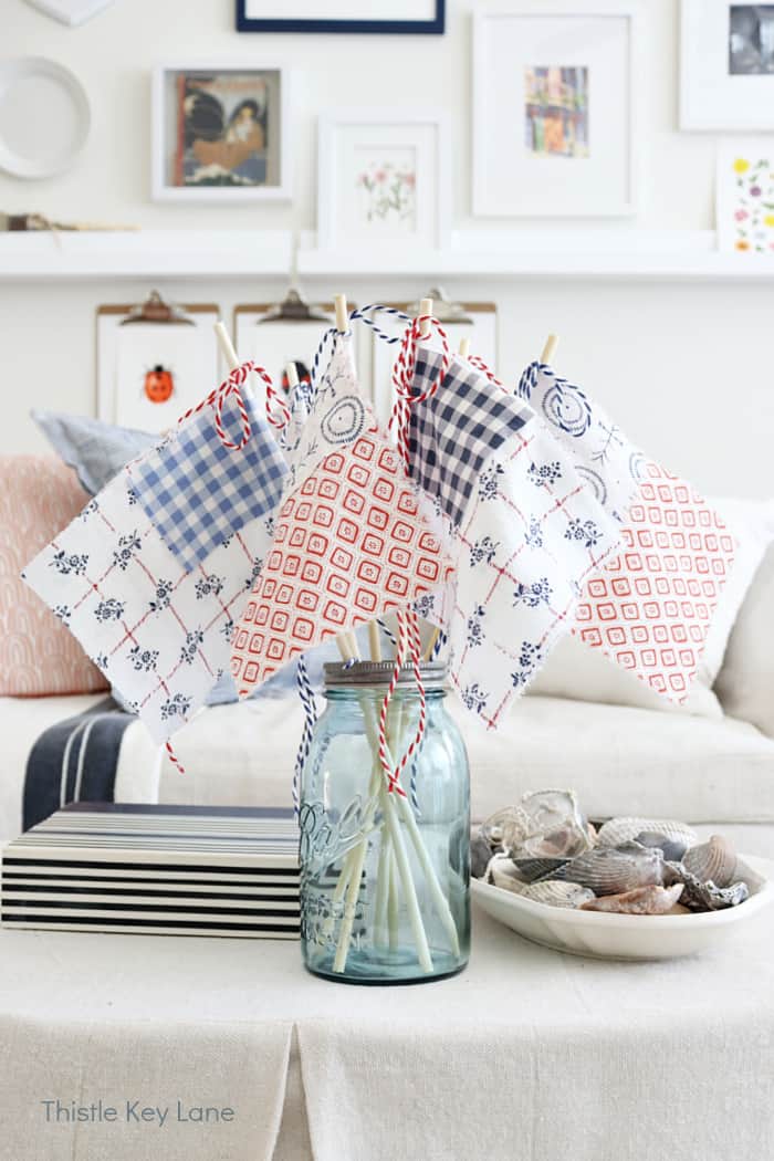 blue mason jar with handmade fabric flags and a white sofa in the background