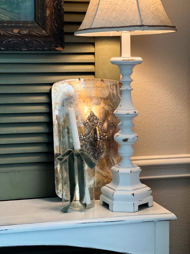 Lamp, silver casserole lid and white candle inside a clear jar with a green bow around it