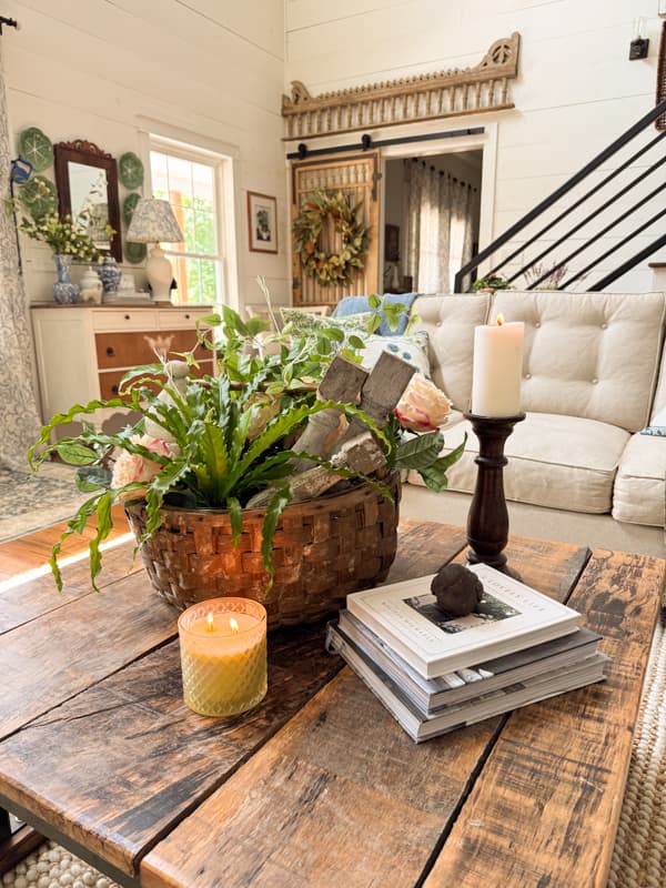 living room with a coffee table that has a basket, candle, and books on top