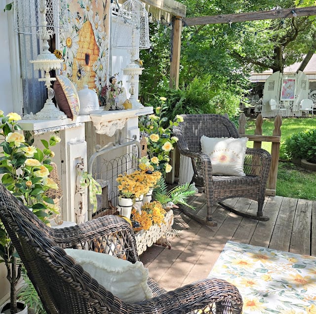 back yard with mantel, yellow flowers, wicker chairs and rug