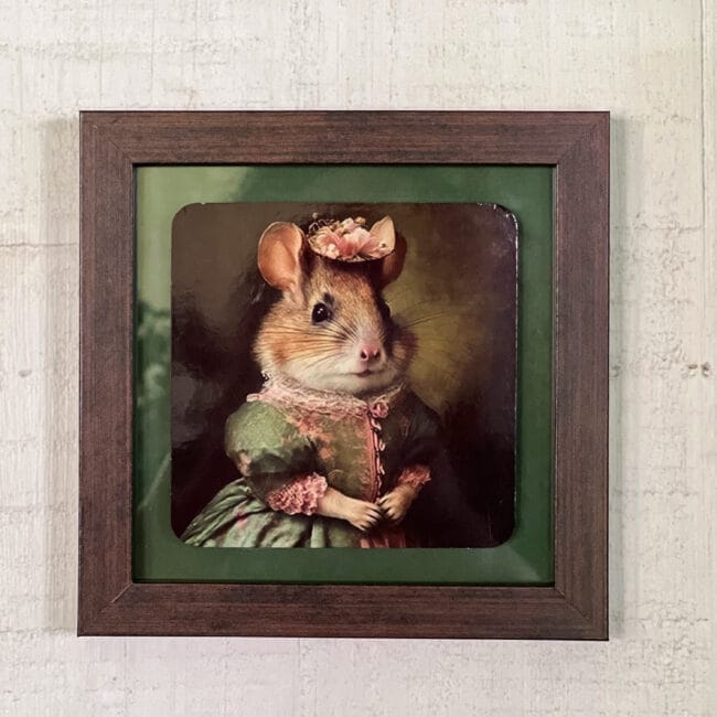 A coaster of a mouse in a dress and hat in a frame