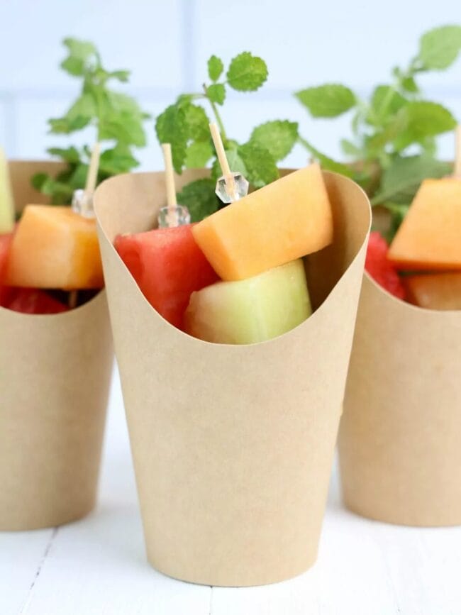 brown charcuterie cups with fruit and beaded toothpick